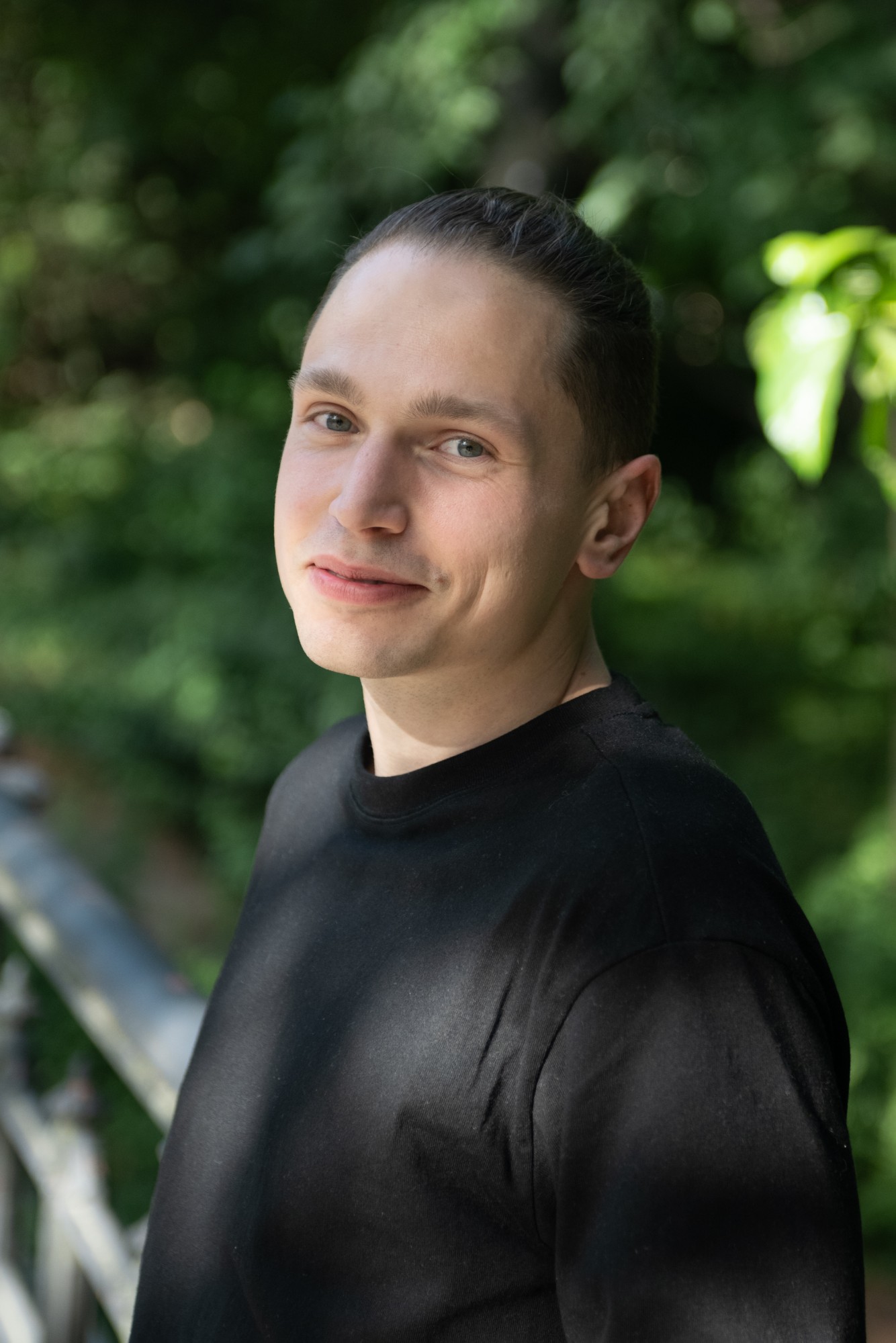 Portrait of Nikita Kissel, smiling, outdoors among green leaves